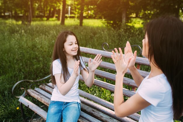 Two girls playing patty-cake in park