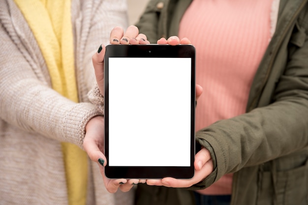 Foto gratuita due ragazze che presentano tablet mockup