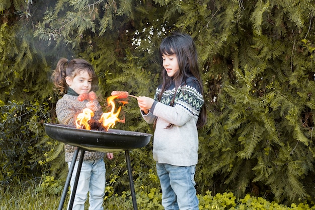 Due ragazze che arrostiscono salsiccie in parco