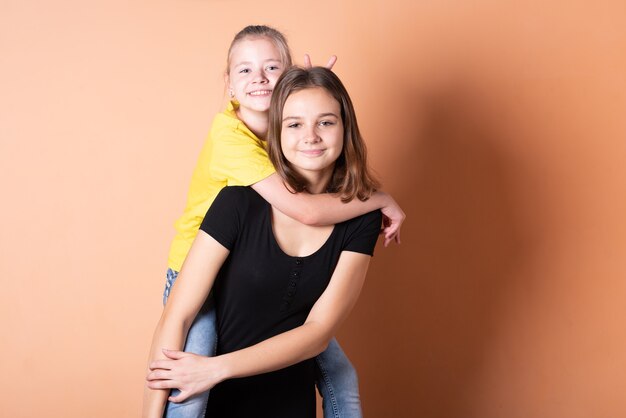 Two girls, sisters, on a light orange background. for any purpose.