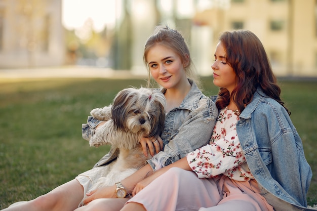 Two girls sitting in a park with a little dog