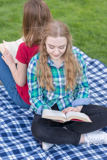 Two girls studying outdoors on picnic blanket