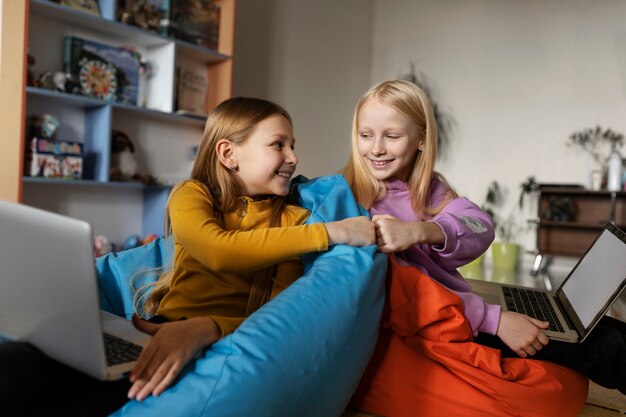 Two girls using laptops and doing a fist bump