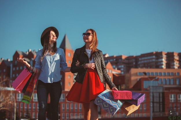 Two girls walking with shopping on city streets