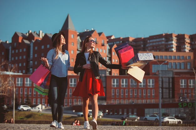 Two girls walking with shopping on city streets