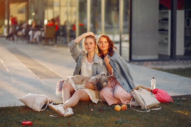 Free photo two girls wallking in a park with a little dog