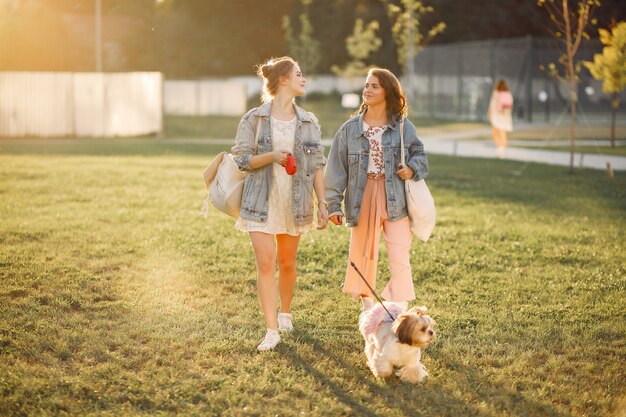 Two girls wallking in a park with a little dog