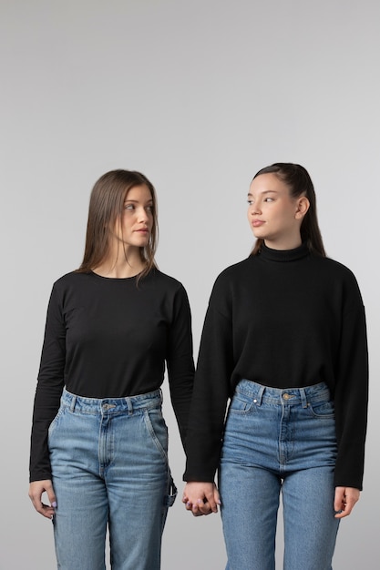 Two girls wearing black t-shirt posing in studio