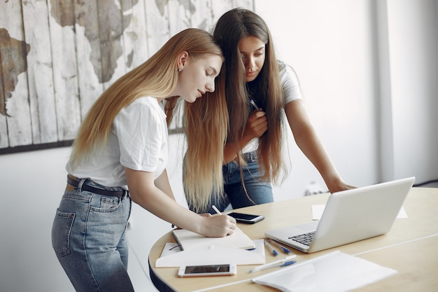 Two girls in a white t-shirts working at the office