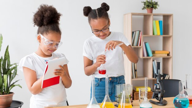 Two girls with safety glasses carrying chemistry experiments