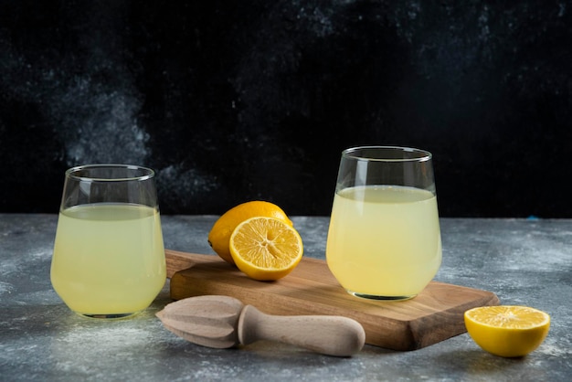 Две стеклянные чашки свежего лимонного сока и деревянная развертка.