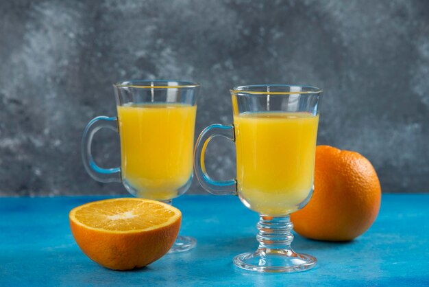 オレンジのスライスとジュースの2つのガラスカップ。