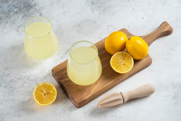 Free photo two glass cups of lemonade and wooden reamer.