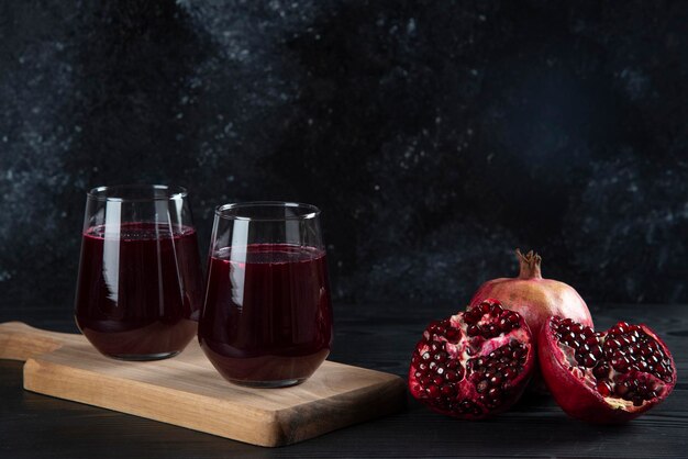 Two glass cups of pomegranate juice on dark. 