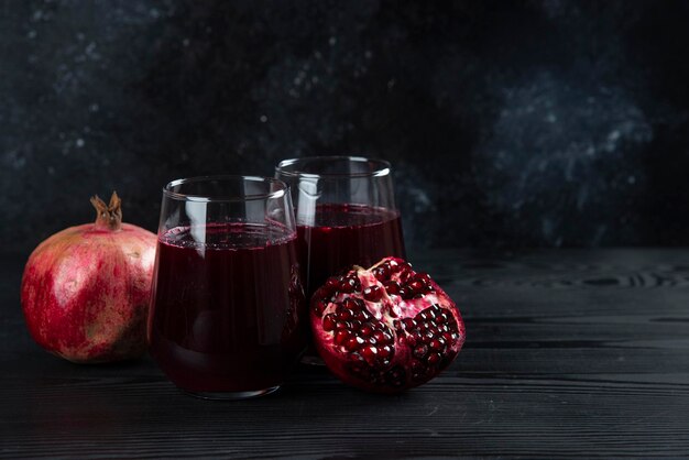 Two glass cups of sweet pomegranate juice on dark. 