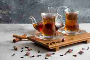 Free photo two glass cups of tea with cinnamon sticks and dried roses.