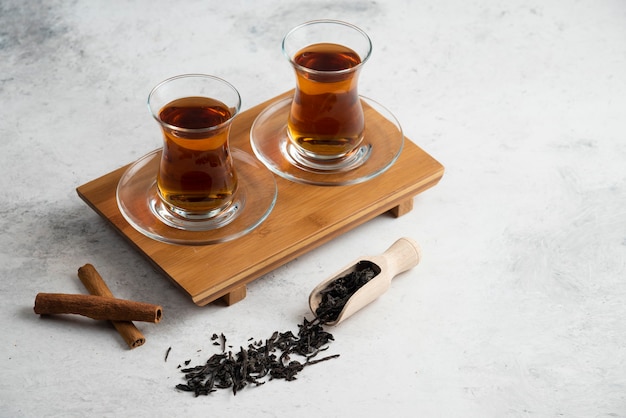 Two glass cups of tea with cinnamon sticks and loose teas.high quality photo