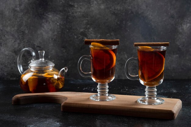 Two glass cups with hot tea and cinnamon sticks.