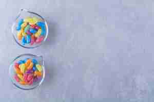 Free photo two glass plates with fruit sweet bean candies on blue-gray surface