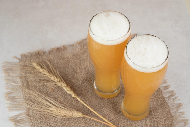 Foto gratuita due bicchieri di birra su tela con grano