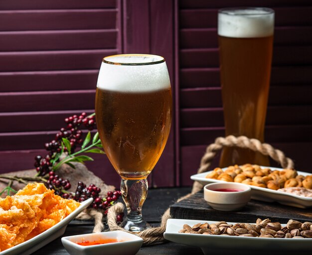 Two glasses of beer served with nuggets, sweet chili sauce and dried fruit