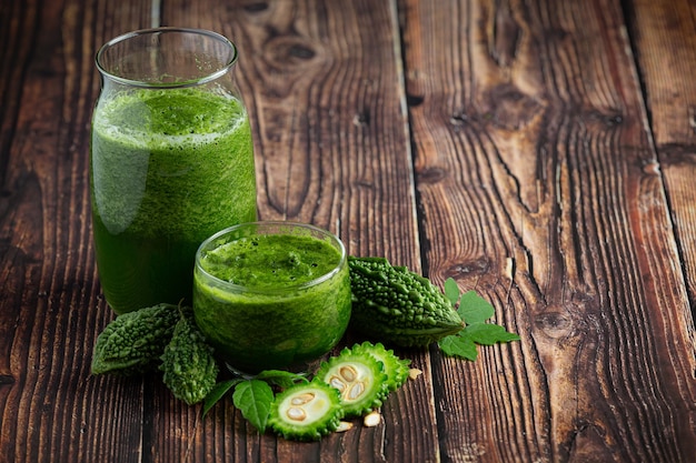 two glasses of bitter gourd smoothie with shopped bitter gourd put on wooden floor