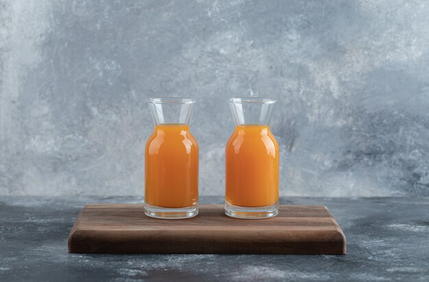 Free photo two glasses of orange juice on wooden board.