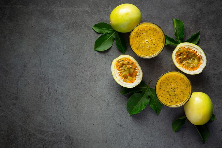 Free Photo two glasses of passion fruit juice and fresh passion fruit cut in half place on dark floor