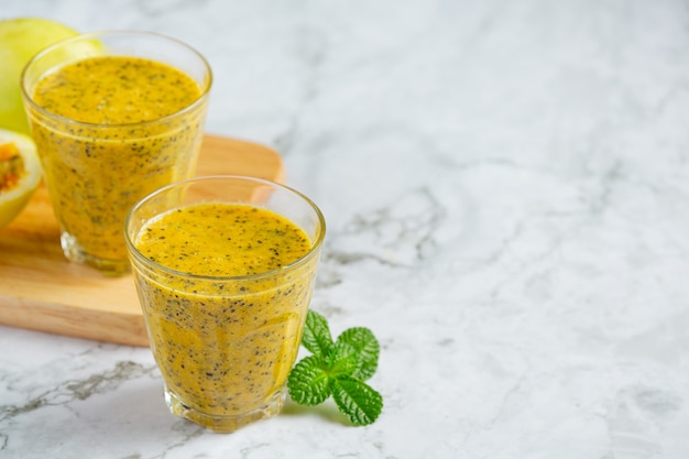 two glasses of passion fruit juice place on white marble floor