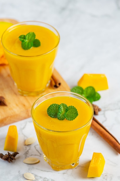 two glasses of pumpkin juice place on white marble  floor