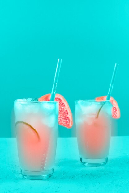 Two glasses of refreshment grapefruit cocktail on mint background