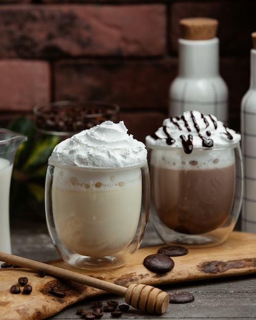 Free photo two glasses of white chocolate mocha and chocolate mocha with whipped cream