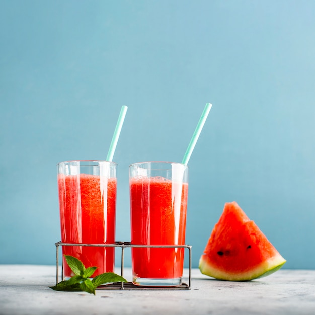Two glasses with watermelon juice and slice beside 