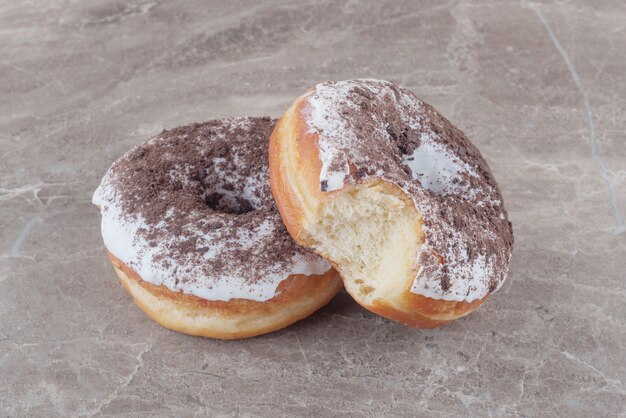 Two glazed donuts on marble 