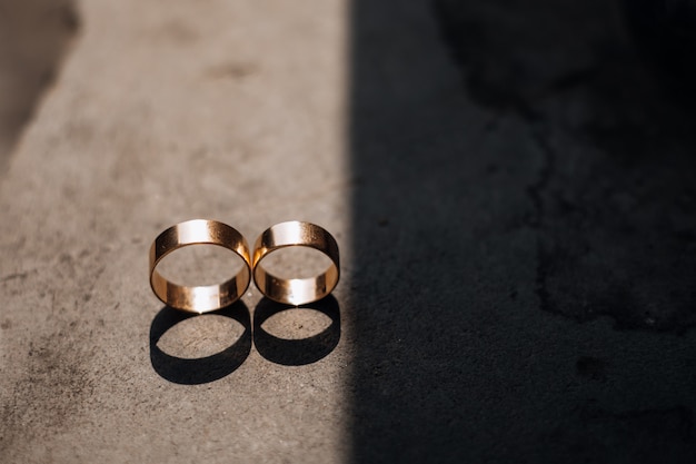 Two golden wedding rings lie in the ray of light