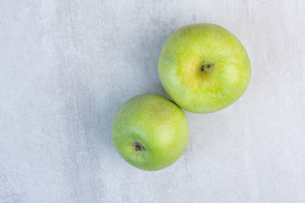 大理石の上に、2つの緑の新鮮なリンゴ。