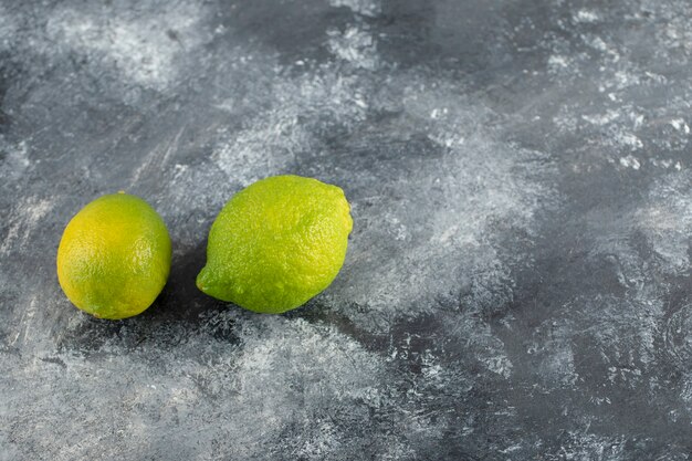 대리석 표면에 두 개의 녹색 신선한 레몬.