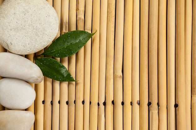 Two green leaves and four white stones on the bamboo mat