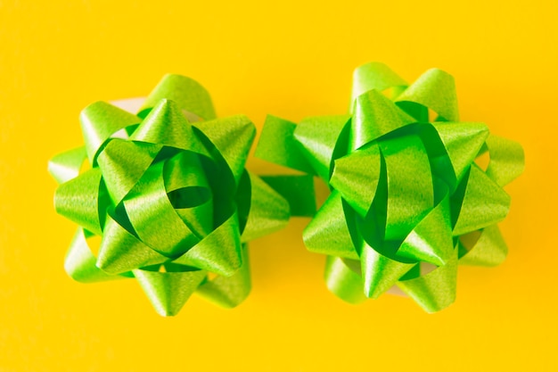 Free photo two green satin ribbon bows on yellow background