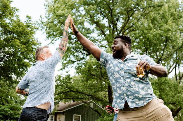 Free photo two guys giving each other a high five at a summer party