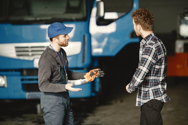 Two guys talking about work. Work in garage near truck. Transfer of documents with goods