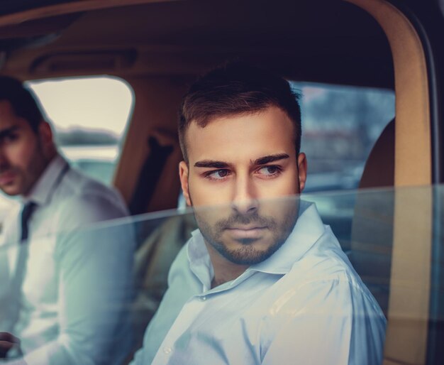 Two guys in a white shirts in the car.