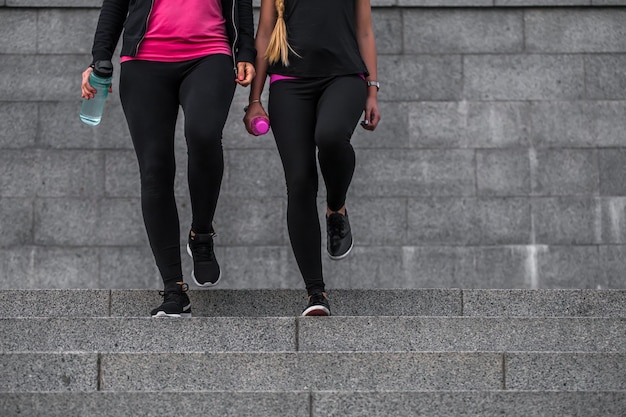 Free photo two gym girls in sports beautiful clothes come up the steps, the concept of fitness and sports healthy lifestyle