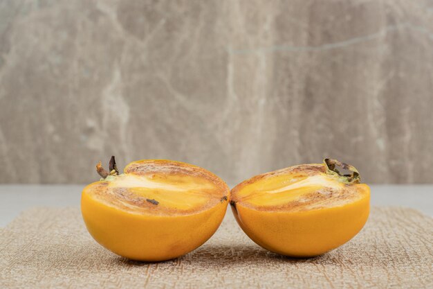 Two half cut slices of persimmons on burlap