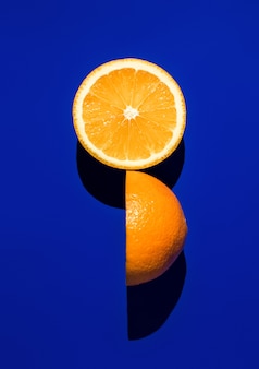 밝은 햇빛에 파란색 배경에 익은 오렌지의 두 반쪽.