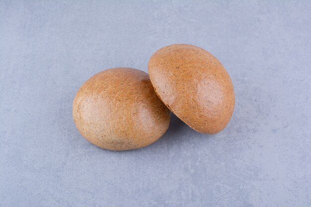 Two hamburger buns on marble surface