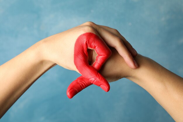 Two hands depict aids awareness sign against blue wall  close up