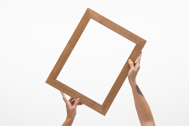 Two hands holding big wooden frame front view