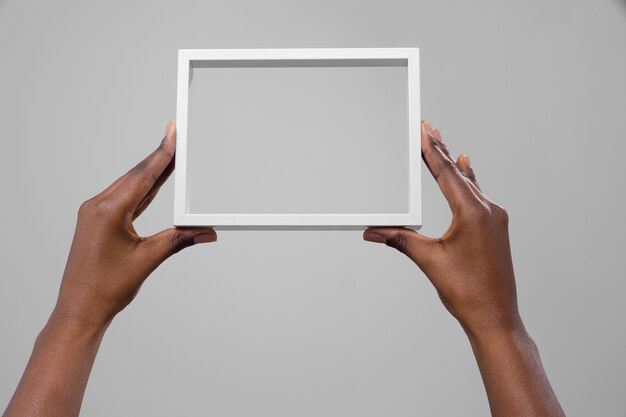 Two hands holding empty white frame