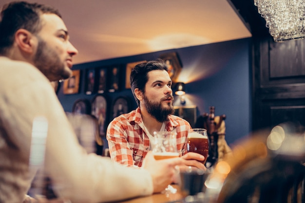 Foto gratuita uomo barbuto bello due che beve birra in pub